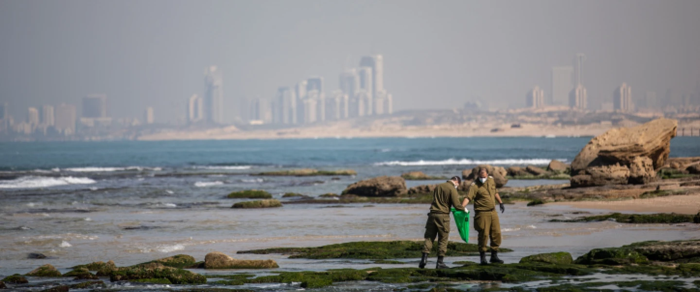Israeli soldiers clean tar off the coast of the Palmachim beach from an offshore oil spill that affected most of Israel's coastline, Feb. 22, 2021. Photo by Yonatan Sindel/Flash90.