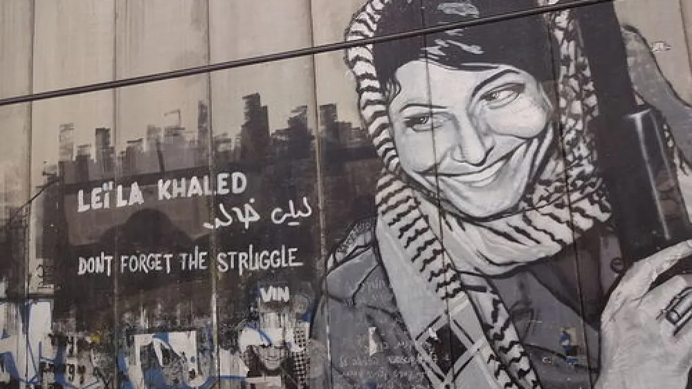 The Israeli security fence in Bethlehem is pictured here painted with graffiti depicting Popular Front for the Liberation of Palestine terrorist Leila Khaled. Rabab Abdulhadi, a professor at San Francisco State University, met with Khaled on a trip funded by the state of California. Credit: Bluewind via Wikimedia Commons.