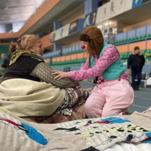 An Israeli medical clown comforting a displaced Ukrainian sheltering in a Moldovan stadium. Photo courtesy of Dream Doctors.