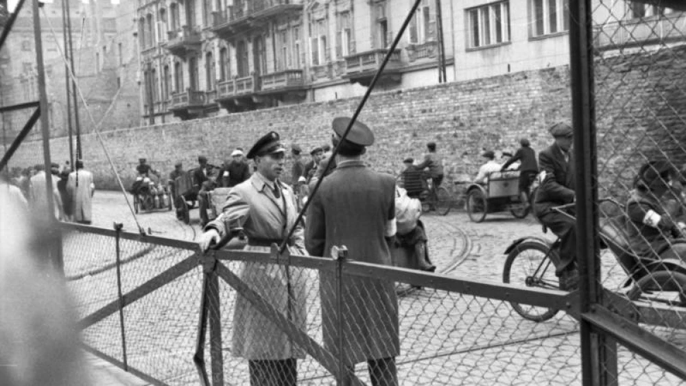 Jewish Ghetto Police guarding the gates of the Warsaw Ghetto, June 1942. Credit: German Federal Archives via Wikimedia Commons.