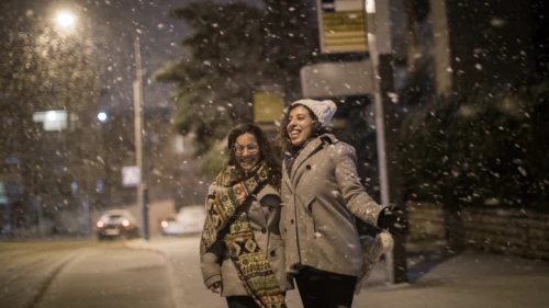 Israeli women enjoy the snow as it falls in the Old Katamon neighborhood of Jerusalem on Jan. 16, 2019. Photo by Hadas Parush/Flash90.