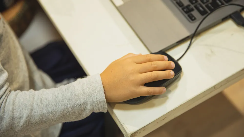 Close-up of a child's hand using a laptop and mouse. Credit: Ryutaro Tsukata/Pexels.