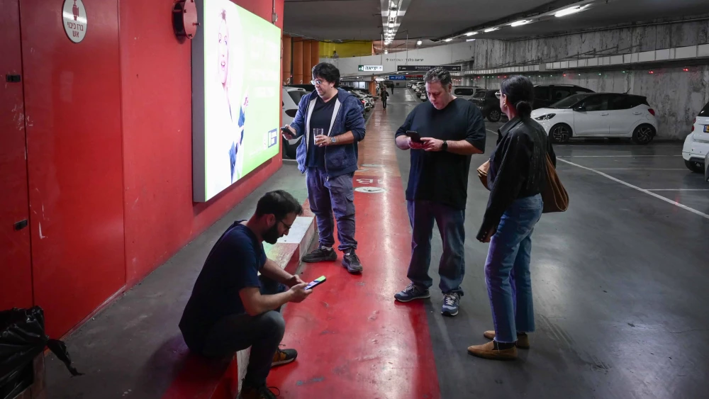 Israelis take cover in a parking garage as a missile alert is activated in Tel Aviv, Dec. 16, 2024. Photo by Avshalom Sassonif/Flash90.