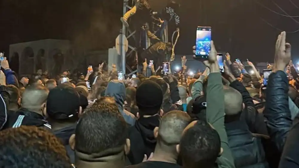 A crowd cheers as the corpses of two men accused of collaborating with Israel are hung on an electrical tower in Tulkarem, Nov. 25, 2022. Source: X.