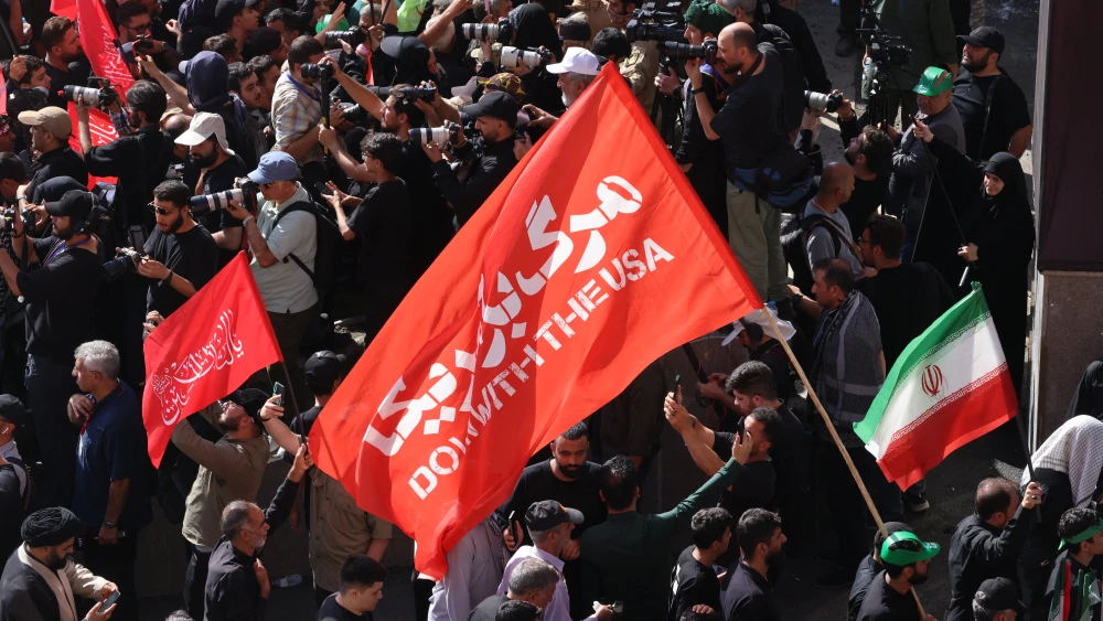 Iranian mourners carry a flag reading "Down with the USA" as they gather for prayers over the body of slain Supreme Leader Ayatollah Ali Khamenei during the second day of funeral ceremonies in Tehran, July 5, 2026. Photo by Atta Kenare/AFP via Getty Images.
