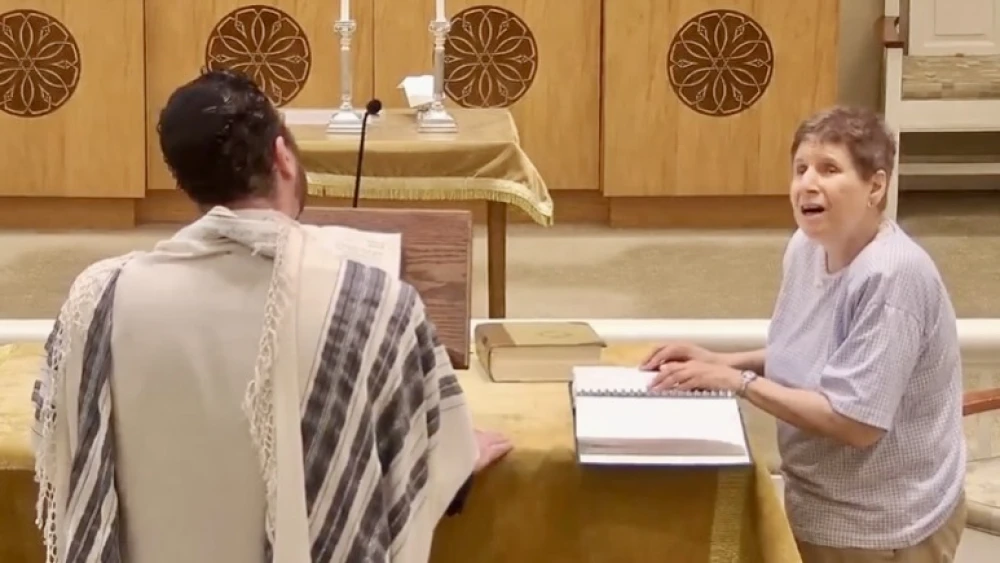 A JBI Library patron reads from the Torah using braill