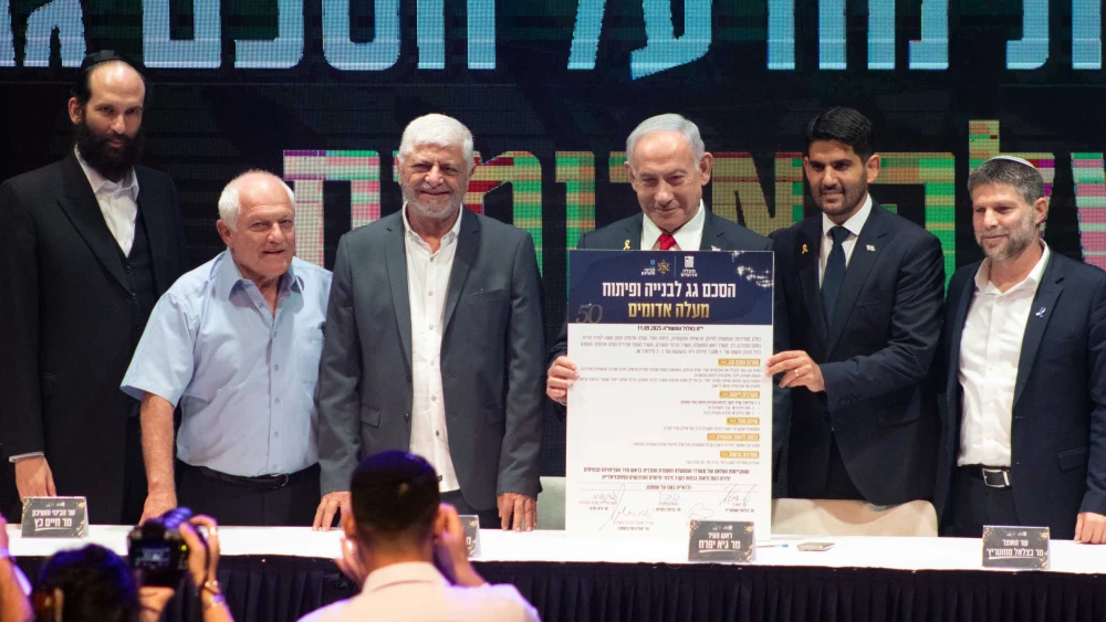 Israeli Prime Minister Benjamin Netanyahu holds up the umbrella agreement at a signing ceremony at the Maale Adumim Cultural Center. Also on stage (from left) are Ministry of Construction and Housing Director-General Yehuda Morgenstern, Housing Minister Haim Katz, former Maale Adumim Mayor Benny Kashriel, current Maale Adumim Mayor Guy Yifrach, and Finance Minister Bezalel Smotrich, Sept. 11, 2025. Photo by David Isaac.