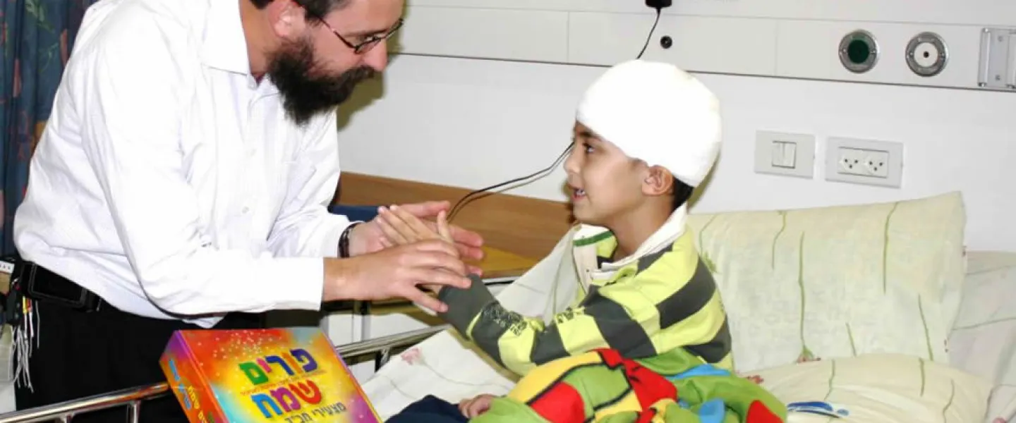 Rabbi Menachem Kutner, director of the Chabad Terror Victims Project, brings a gift to Ural Yelizarov, who was wounded in the head by a Grad rocket in Beersheva during “Operation Cast Lead” in 2014. Credit: CTVP.