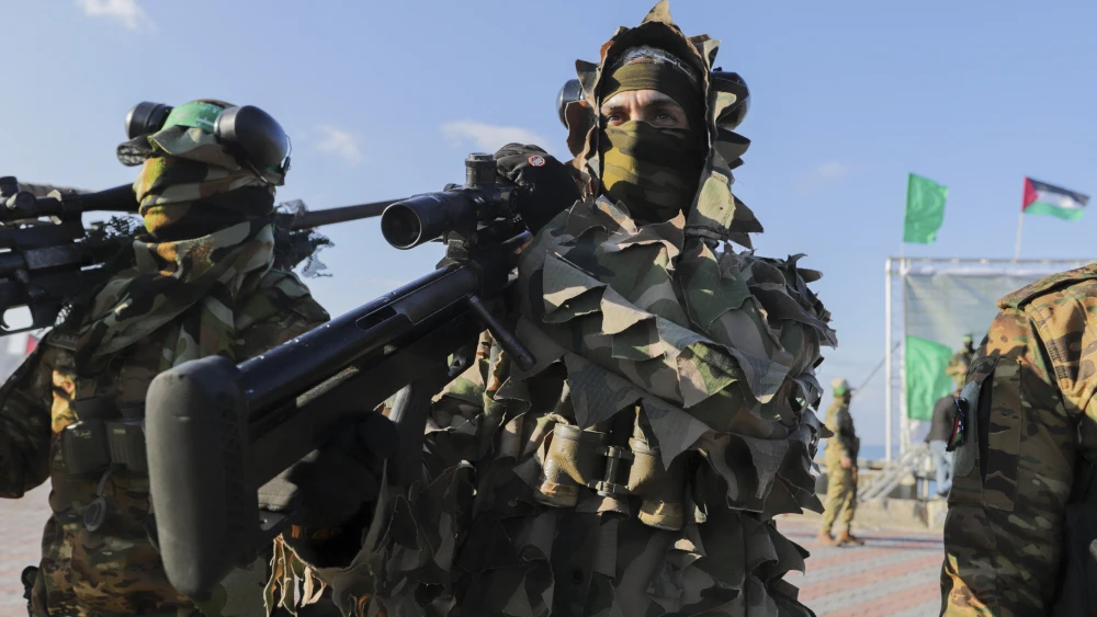 A Hamas fighter carries a sniper rifle on his shoulder as he secures an area before the handover of an Israeli-American hostage to a Red Cross team in Gaza City on February 1, 2025, as part of the fourth hostage-prisoner exchange. Ranks of Hamas fighters formed up on Gaza's beachfront on February 1 for the handover of an Israeli-American hostage Keith Siegel in a show of force against the dramatic backdrop of breaking waves. (Photo by Saeed Jaras / Middle East Images / Middle East Images via AFP) (Photo by SAEED JARAS/Middle East Images/AFP via Getty Images)