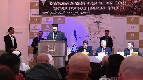 Click photo to download. Caption: Father Gabriel Naddaf addresses Christian IDF soldiers in December 2014, with Israeli Prime Minister Benjamin Netanyahu (sitting at table, in center) in attendance. Credit: Maor X via Wikimedia Commons.