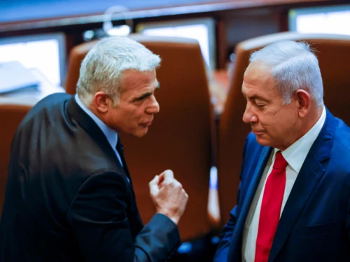 Opposition leader Yair Lapid, then the foreign minister, walks past Prime Minister Benjamin Netanyahu, at the time the leader of the opposition, at the Knesset in Jerusalem, Nov. 8, 2021. Photo by Olivier Fitoussi/Flash90.