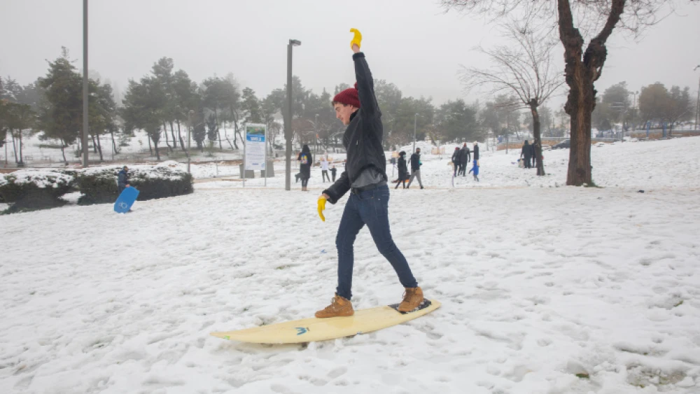 An Israeli teen uses a surfboard to play in the snow in Jerusalem on Feb. 18, 2021. Photo by Olivier Fitoussi/Flash 90.