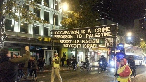 In a protest against the Ferguson verdict on Nov. 24 in Seattle, a sign uses the situation as a platform to promote a boycott of Israel. Credit: The Mike Report.