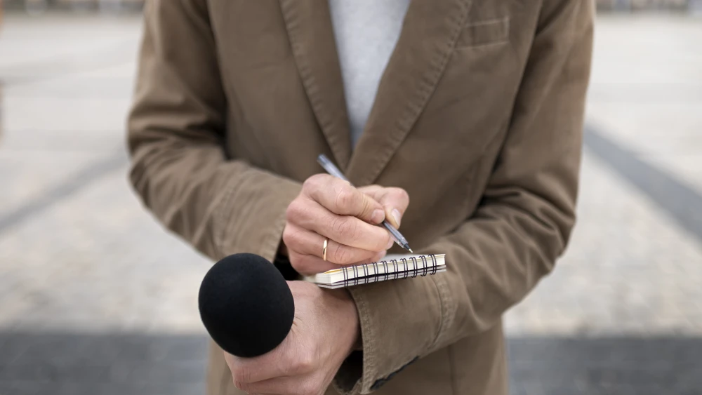 Close-up of a reporter taking notes. Credit: Magnific.