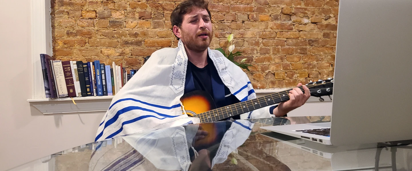 Levi Cohen at his computer as he sings melodies welcoming the onset of Shabbat. Credit: Dovid Zaklikowski.