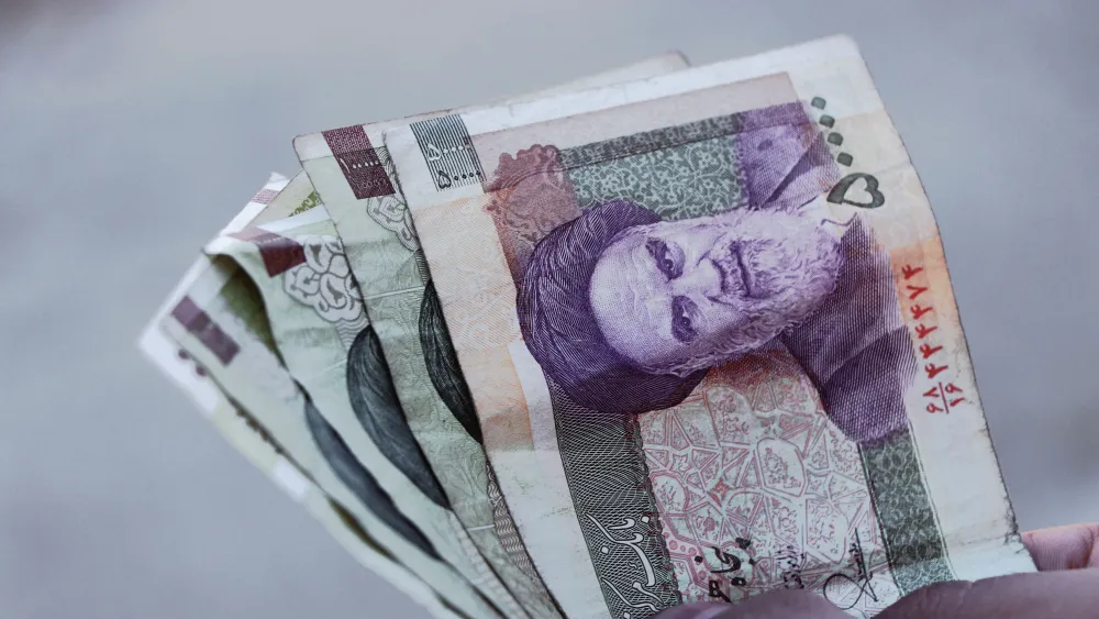 A person holding Iranian rial banknotes. Credit: Amir Ghoorchiani/Pexels.