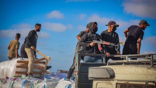 Armed Palestinians sit on trucks carrying humanitarian aid near the Zikim border crossing between Israel and Beit Lahia in the northern Gaza Strip, June 25, 2025. Photo by Ali Qariqa/Flash90.