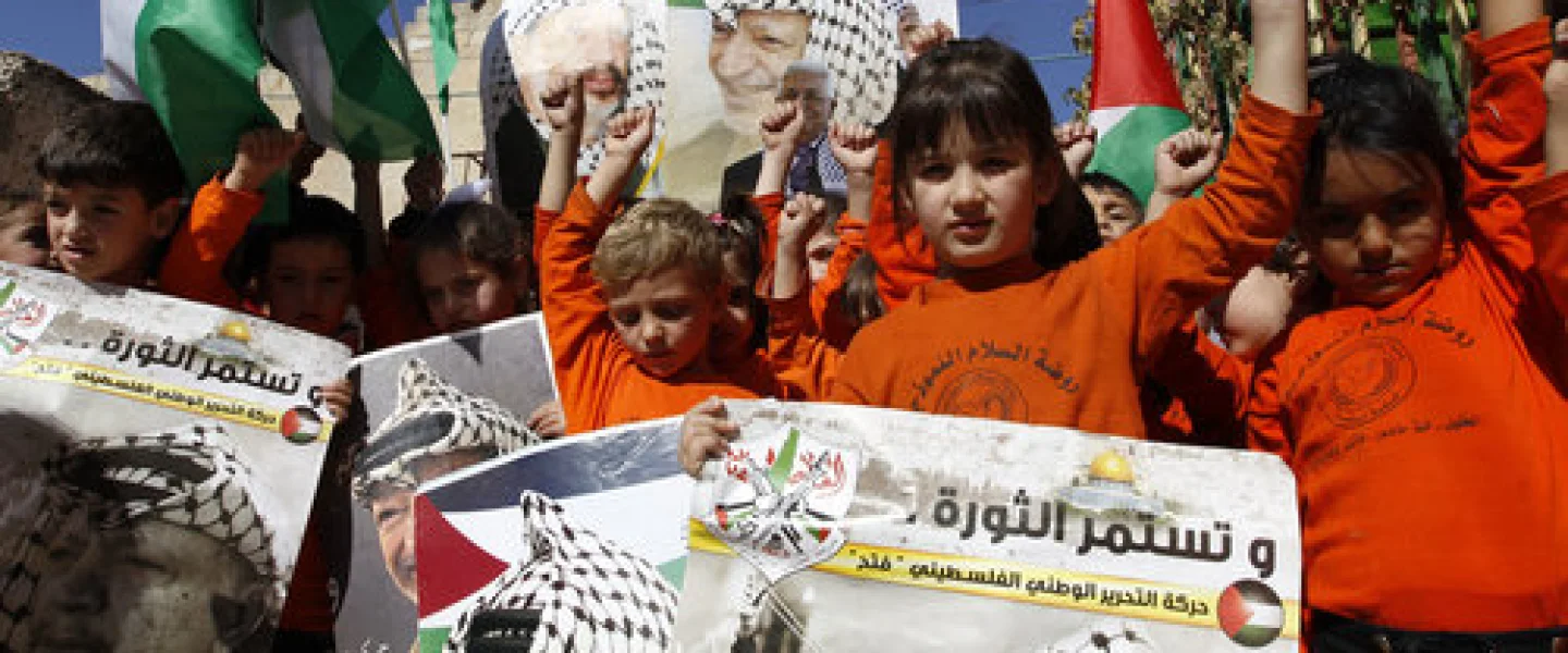 Palestinian children hold posters with the picture of former Palestinian head Yasser Arafat and current Palestinian Authority leader Mahmoud Abbas during a rally in Hebron marking the 12th anniversary of Arafat’s death Nov. 10, 2016. Credit: Wisam Hashlamoun/Flash90.
