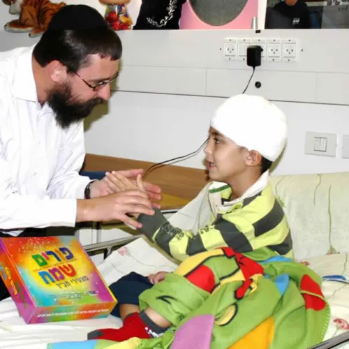 Rabbi Menachem Kutner, director of the Chabad Terror Victims Project, brings a gift to Ural Yelizarov, who was wounded in the head by a Grad rocket in Beersheva during “Operation Cast Lead” in 2014. Credit: CTVP.
