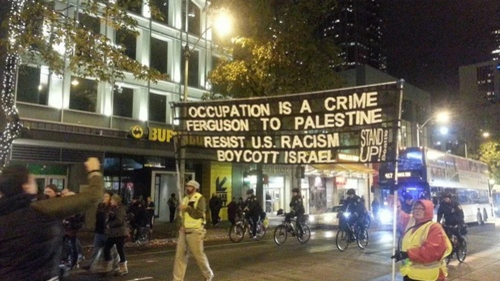 In a protest against the Ferguson verdict on Nov. 24 in Seattle, a sign uses the situation as a platform to promote a boycott of Israel. Credit: The Mike Report.