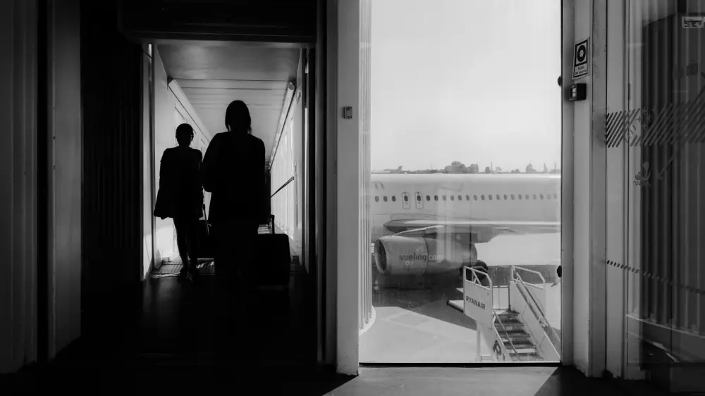 Travelers walking down a jet bridge to board a plane. Credit: Masi/Pexels.