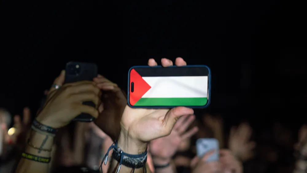 A person displaying a Palestinian flag on a cellphone screen. Credit: Noland Live/Pexels.