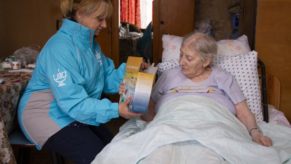 Continuing JDC’s long-held tradition of matzah delivery for Passover, a volunteer provides matzah to an elderly client in Odessa, Ukraine. Credit: Courtesy.