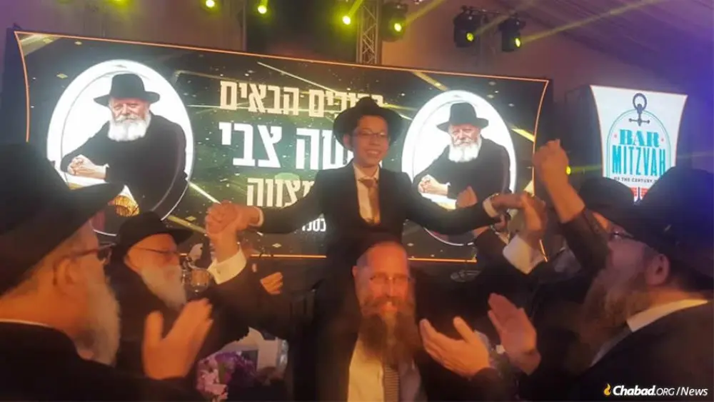 A celebratory bar mitzvah crowd dances with Moshe Holtzberg, orphaned in the Mumbai Chabad center massacre that took the lives of his parents 11 years ago this week. Credit: Chabad.org/News.