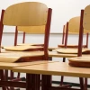 Chairs propped up on desks in an empty classroom. Credit: Taken/Pixabay.