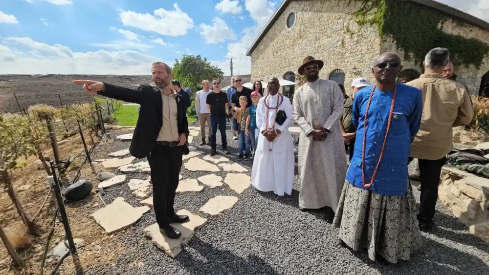 Yisrael Gantz (left), head of the Binyamin Regional Council and chairman of the Yesha Council, gestures toward the surrounding landscape while hosting King Ogiame Atuwatse III of Nigeria’s Warri Kingdom (center, wearing hat and glasses) and his delegation at Psagot Winery, Oct. 6, 2026. Photo courtesy of Binyamin Regional Council.