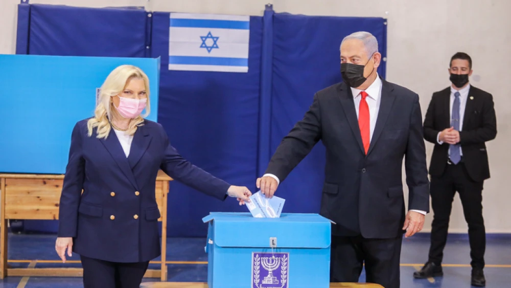 Israeli Prime Minister and head of the Likud Party Benjamin Netanyahu casts his vote in the fourth elections in two years, together with his wife, Sara Netanyahu, at a voting station in Jerusalem, on March 23, 2021. Photo by Marc Israel Sellem/POOL.