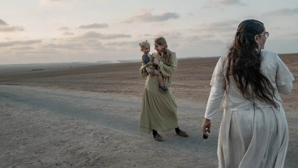 An Israeli Jewish mother holds her child and poses for a photo at the start of Shabbat across the Gaza Strip's northern borders on Aug. 22, 2025 in Israel. Photo by Elke Scholiers/Getty Images.