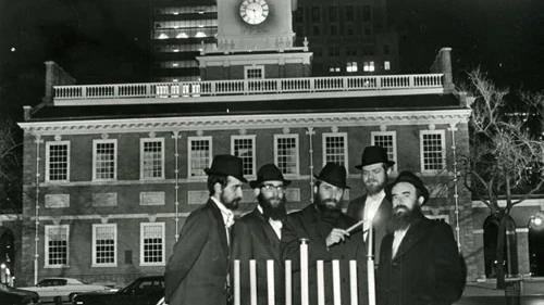 Rabbi Abraham Shemtov, right, in front of Independence Hall in Philadelphia at the lighting of the first-ever public menorah in 1974. With him were yeshivah students who helped build the menorah from scratch. Credit: Lubavitcher Center/Chabad.org.