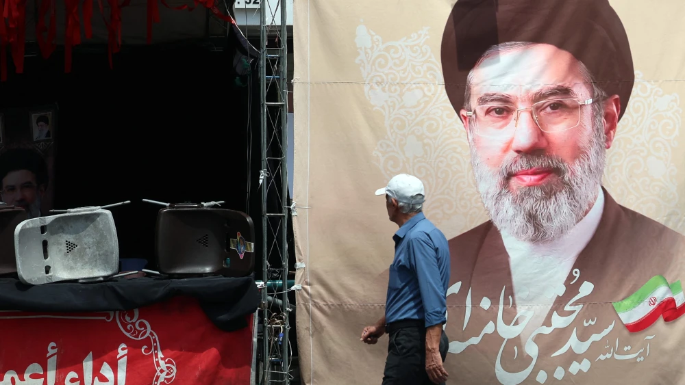 An Iranian man walks past a billboard carrying a picture of Iran' supreme leader Mojtaba Khamenei erected along a street in Tehran on May 28, 2026. Photo by AFP via Getty Images.