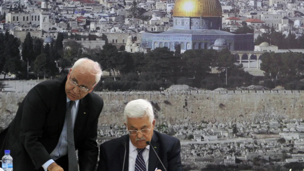 P.A. leader Mahmoud Abbas (right) and Palestinian chief negotiator Saeb Erekat sign an application to U.N. agencies in the West Bank city of Ramallah on April 1, 2014. Photo by Issam Rimawi/Flash90.