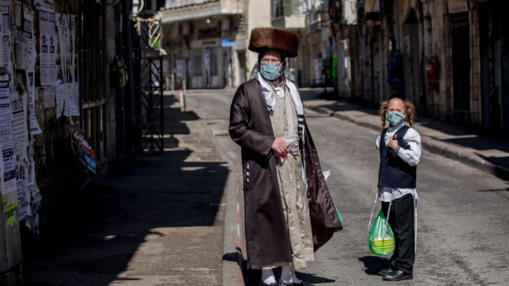 An ultra-Orthodox man and his son shop for goods in the Mea Shearim neighborhood of Jerusalem on April 12, 2020. Photo by Yonatan Sindel/Flash90.