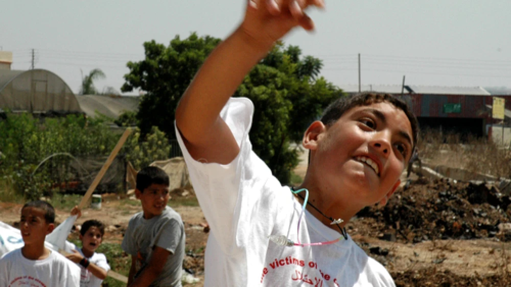 Click photo to download. Caption: A Palestinian boy throws a stone at Israel's security fence. Credit: Justin McIntosh.