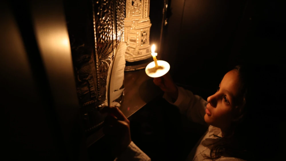 Sahar Amsalem and his son Shimon perform search for remains of leaven after cleaning their home, in Tzfat on the night before Passover, on April 4, 2023. Photo by David Cohen/Flash90.