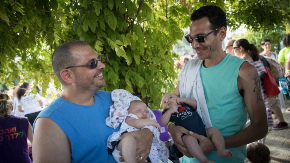 A couple holds their children, conceived through a surrogate mother, during the Pride Parade in Jerusalem, Thursday, Aug. 2, 2018. Photo By Hadas Parush/Flash90.