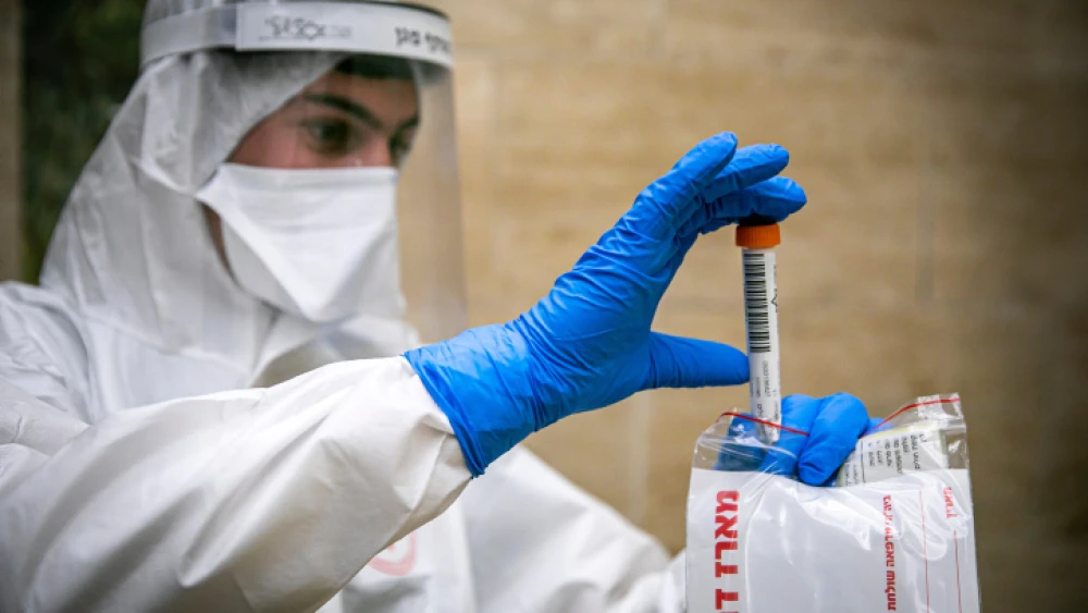 A Magen David Adom medical team member handles a coronavirus test sample in Jerusalem, on April 17, 2020. Photo by Olivier Fitoussi/Flash90.