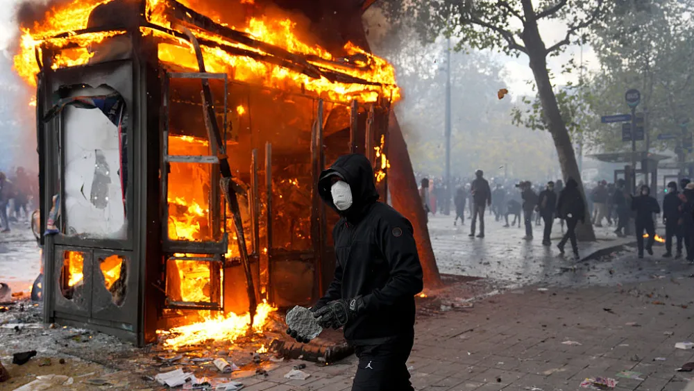 A protester holds a rock as a kiosk burns during a demonstration in Paris on Oct. 17, 2026. Photo by Carl Court/Getty Images.