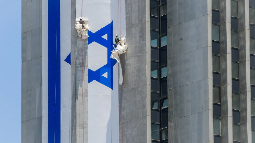 Israeli workers hang a large Israeli flag in Ramat Gan, June 8, 2022. Photo by Avshalom Sassoni/Flash90.