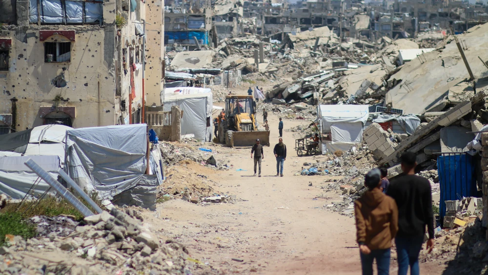 People walk past destroyed homes on April 22, 2026 in Gaza City, Gaza. The homes were destroyed by Israeli airstrikes earlier in the war. A fragile truce has been in place since last October, two years after the outbreak of war between Israel and Hamas in 2023. Photo by Ahmad Hasaballah/Getty Images.