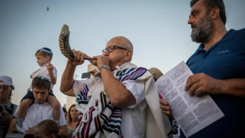 An Israeli blows a shofar as others perform Tashlich on the afternoon of Rosh Hashanah at the beach in Tel Aviv, on Sept. 10, 2018. Photo by Yonatan Sindel/Flash90.