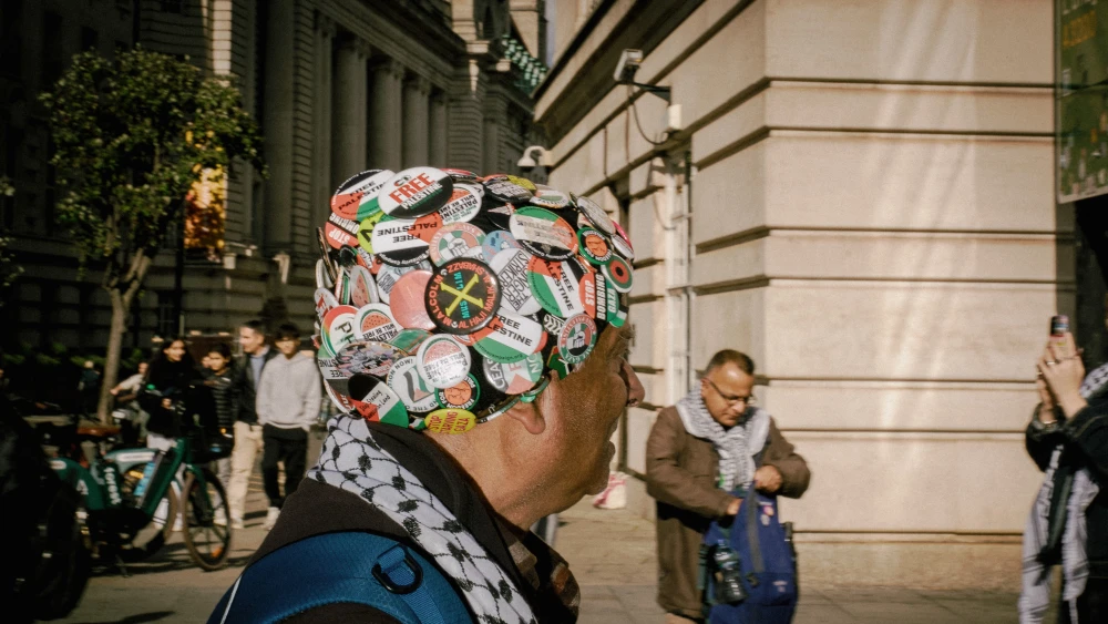 A demonstrator wearing a cap covered in pro-Palestinian and anti-Israel badges alongside a keffiyeh takes part in a march in central London, Saturday, Oct. 10, 2026, marking three years since Hamas sparked the war in Gaza with its Oct. 7 terrorist attack against Israel. Photo by Emil Lombardo/Hans Lucas/AFP via Getty Images.
