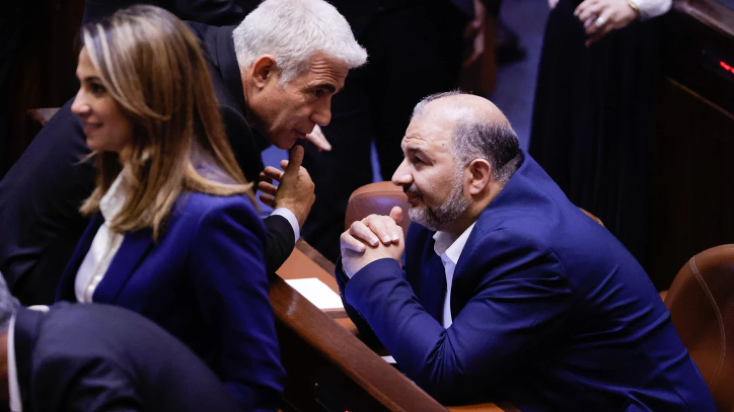 Israeli Foreign Minister Yair Lapid (center) speaks with Mansour Abbas, the head of the Ra'am Party, in the Knesset assembly hall, June 21, 2021. Photo by Olivier Fitoussi/Flash90.