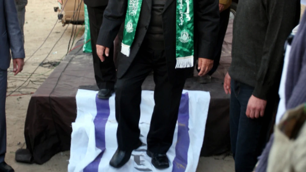 Hamas leader Mahmud al-Zahar steps on an Israeli flag, with Arabic scrawled on it, as part of celebrations in Gaza City marking the 23rd anniversary of the terror group’s founding, Dec. 9, 2010. Photo by Mohammed Othman/Flash90.