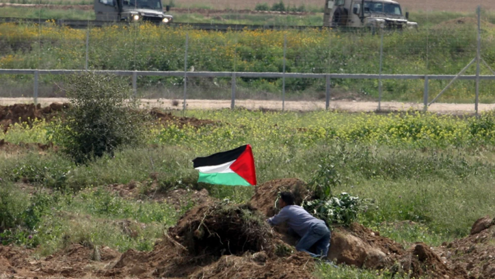 A Palestinian man waves the Palestinian flag near Israeli soldiers by the border fence near Gaza City in March 2010. Photo by Wissam Nassar/Flash90.