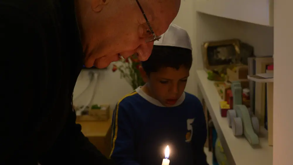 Israeli President Reuven Rivlin seen with his grandson looking with a candle for any sign of "chametz" as he prepares for the Jewish holiday of Passover, April 2, 2015. Credit: Amos Ben Gershom/GPO.