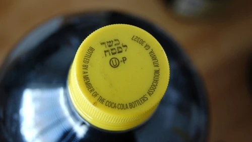 A kosher-for-Passover bottle of Coca-Cola, distinguished from ordinary Coca-Cola bottles by its yellow cap and special "hechsher." Credit: Mark H. Anbinder via Flickr.com.